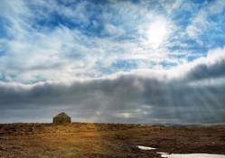 sun rays over a stone cabin on the plains