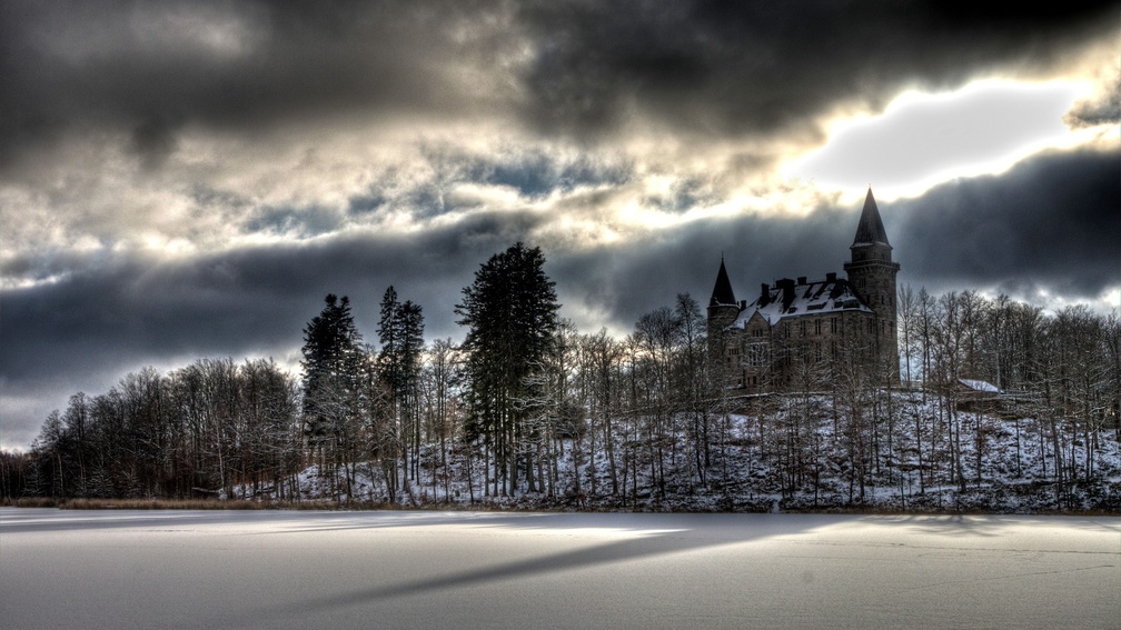 castle on a hill above a frozen lake hdr