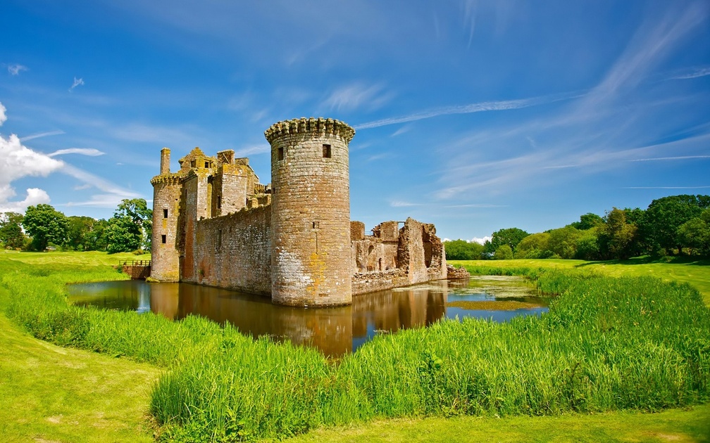 a pond around a beautiful castle ruins