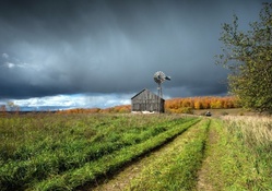 barn and windmill under stormy clouds
