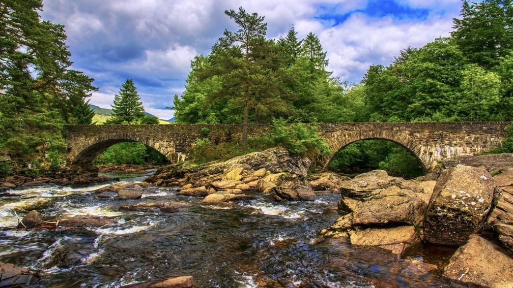 old stone bridge over rocky stream hdr