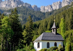 lovely chapel in forest under grand mountains