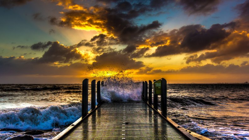 fishing pier in rough sea at sunset