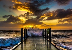 fishing pier in rough sea at sunset