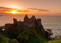 the ruins of dunluce castle in ireland at sunset