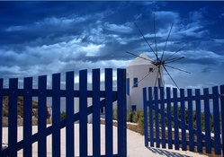 greek windmill behind blue fence