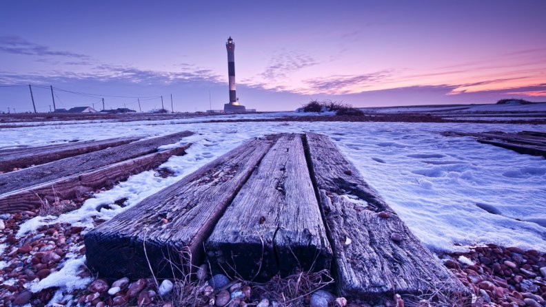 tall lighthouse in a purple winter evening