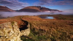 stone wall to mountains draped by fog