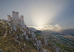 sun rays illuminating mountaintop castle ruins