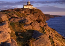lighthouse on a rocky cliff at sunset