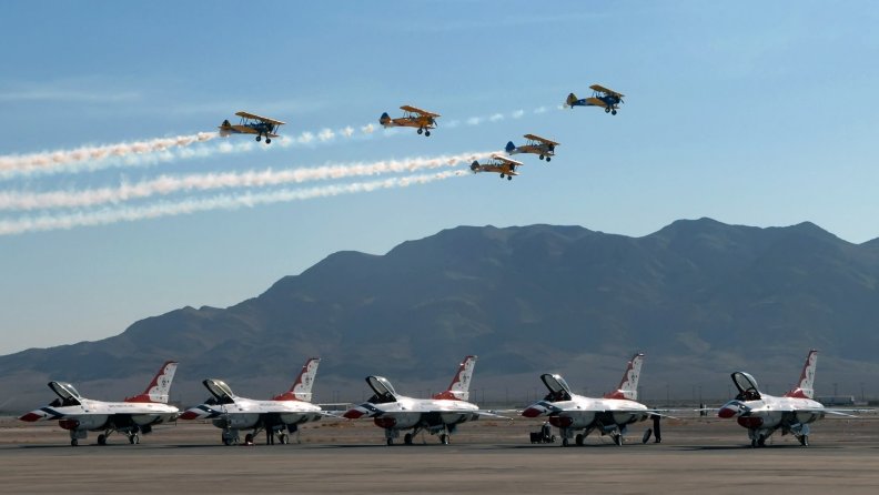 a flight of biplanes over f16 thunderbirds