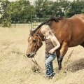 YOUNG COWGIRL LEADING HORSE