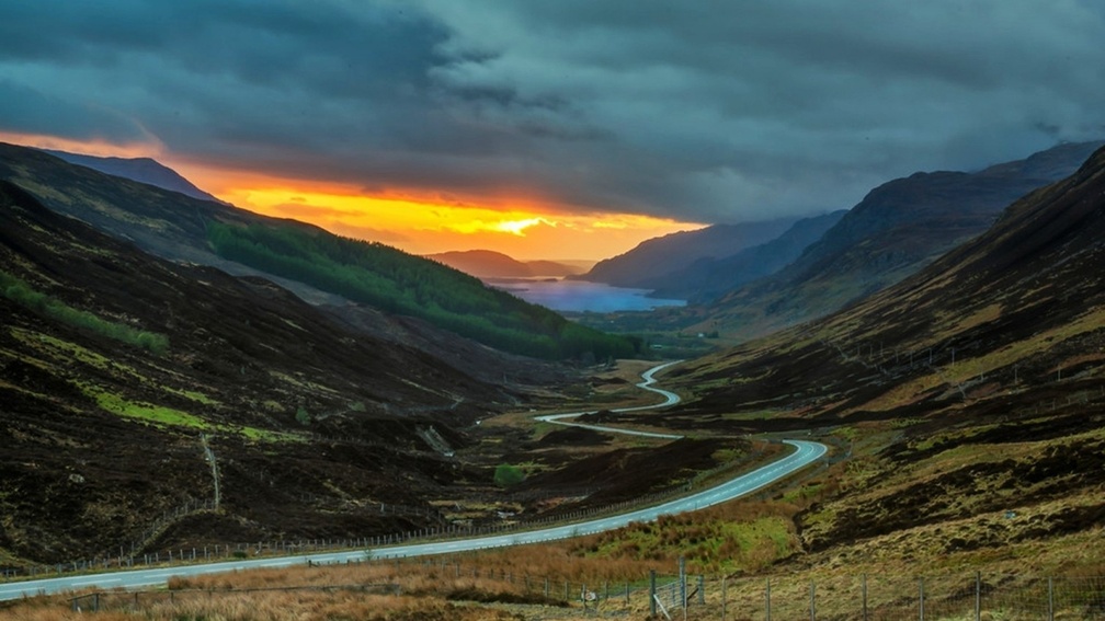 road down a scottish valley at sunset