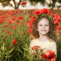 Little girl with flowers in the poppy field