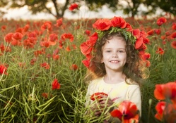 Little girl with flowers in the poppy field