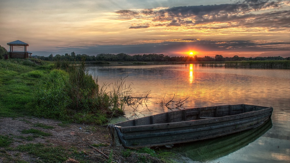 old wooden boat on lakeshore at sunset hdr