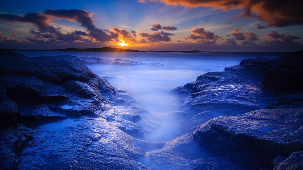 sunrise over blue rocky seashore
