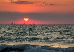 sunset over cityscape beyond the sea