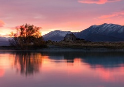 stone lake house in a pink sunrise