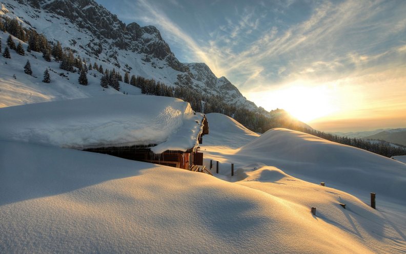 mountain_cabin_covered_in_snow_at_sunrise.jpg