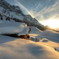 mountain cabin covered in snow at sunrise