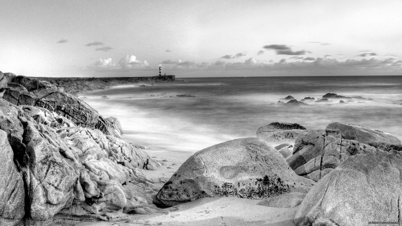 lighthouse on a stone pier in grayscale hdr