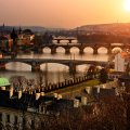 sunset over a river with many bridges in prague