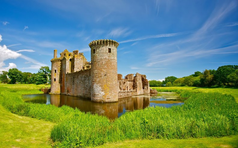 a pond around a beautiful castle ruins