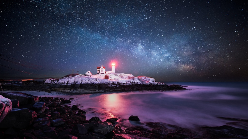 lighthouse on a rocky point under starry night