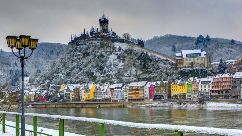 castle on a hill above a river town in winter