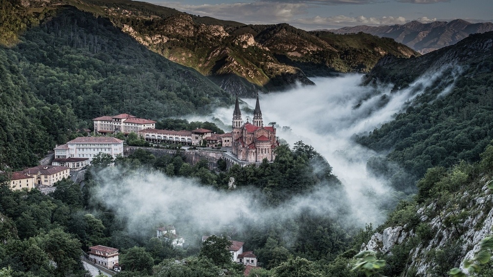 monastery on a hill in a foggy valley