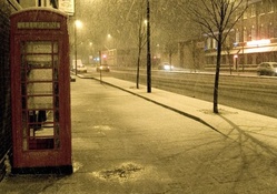 phone booth on a british sidewalk in a snow shower