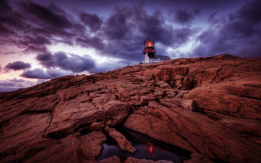 red light lighthouse on rocky shore hdr
