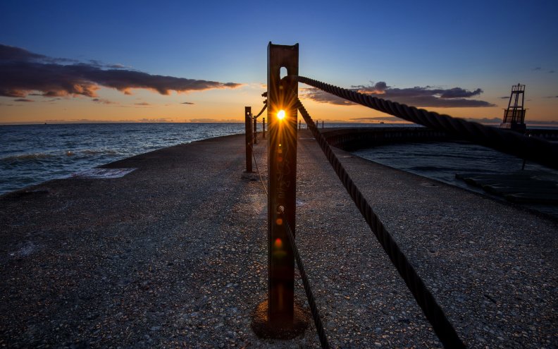 sunset_through_a_metal_post_on_a_pier.jpg