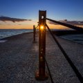 sunset through a metal post on a pier