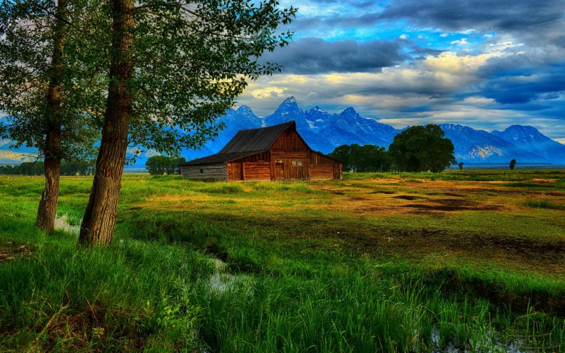 beautiful_barn_on_the_plains_by_a_mountain_range.jpg