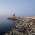 lighthouse on a rock pier at a misty sea