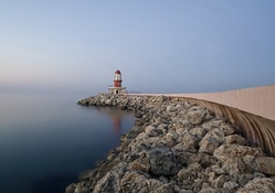 lighthouse on a rock pier at a misty sea