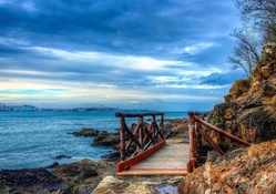 little wooden bridge over rocky seashore hdr
