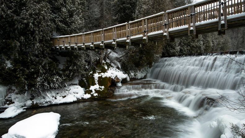 lovely pedestrian bridge over waterfall in winter