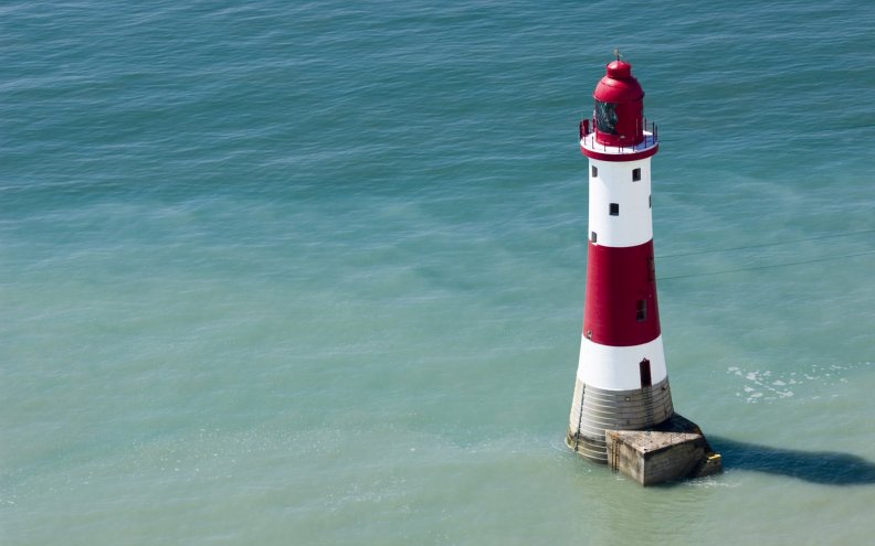 red_and_white_lighthouse_at_sea.jpg
