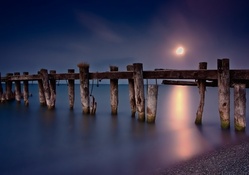 old pier in a misty sea under a moon