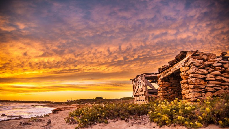 stone_and_wooden_huts_on_a_beach_at_sunset.jpg