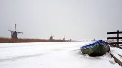 row of windmills along a wintry channel
