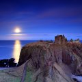moon over castle ruins on a coastal cliff