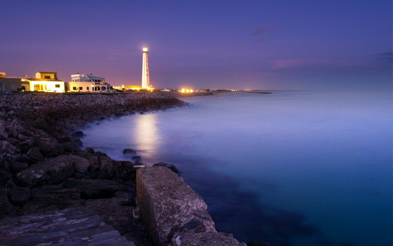 lit_lighthouse_at_a_night_seashore.jpg