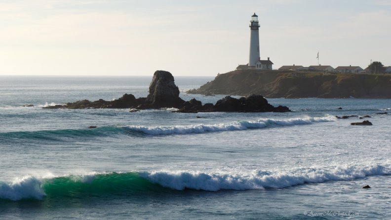 lighthouse_above_turqoise_waves_on_a_rocky_beach.jpg