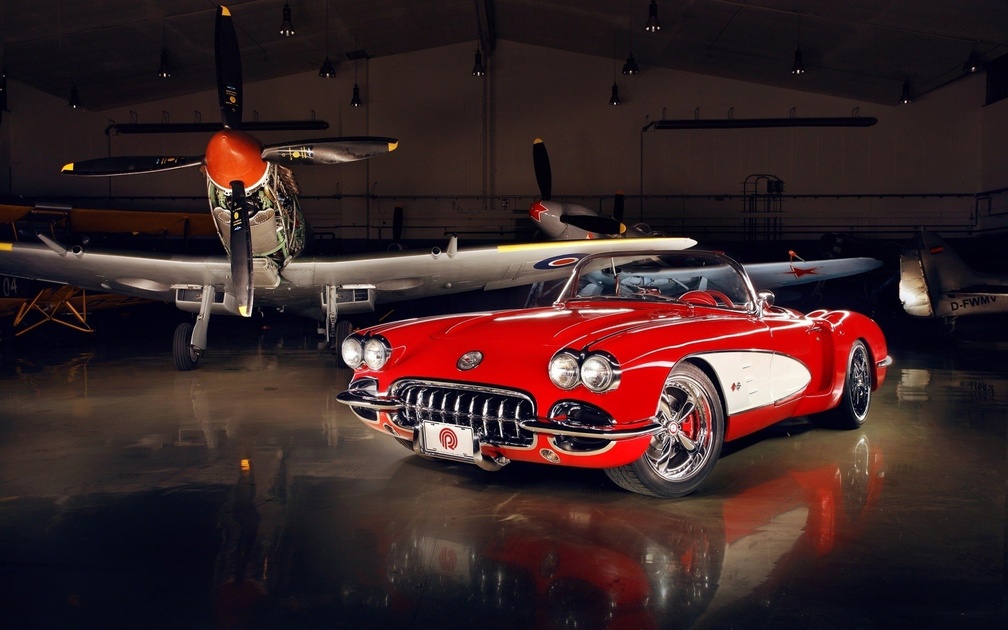 aircraft hanger and red car