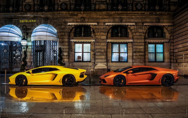 two lamborghinis parked in front of the ritz